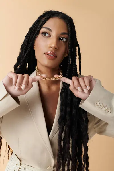 A young woman with long braided hair adjusts a gold chain necklace. — Stock Photo