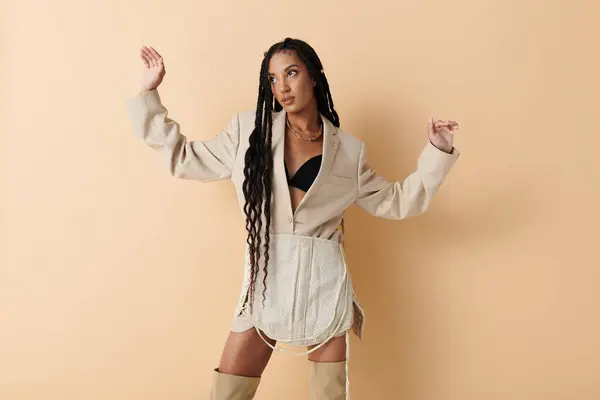 A young woman with long, curly black hair poses confidently in a beige blazer — Stock Photo