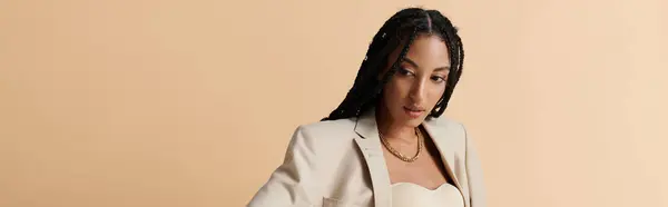 A young African American woman poses in fashionable attire against a beige background. — Stock Photo