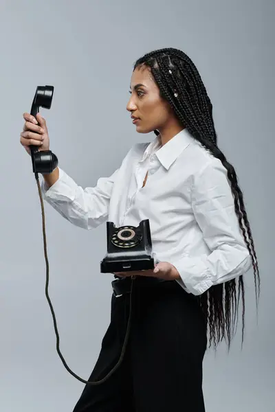 A young woman with long black braids poses with a vintage phone. — Stock Photo