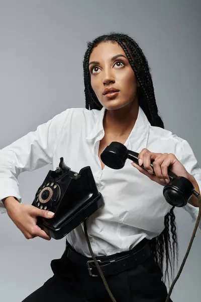A young woman in a white shirt holds a vintage phone and stares up at something out of frame. — Stock Photo