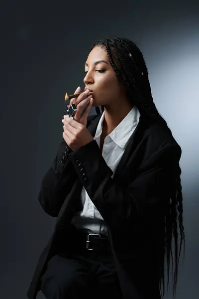 A stylishly dressed young woman lights a cigar, exuding confidence and sophistication. — Stock Photo