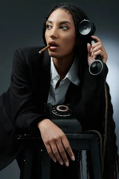 A stylish young Black woman with long braids poses while talking on a vintage phone and holding a cigar. — Stock Photo