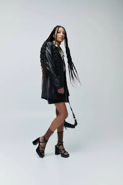 A stylish African American woman in her 20s poses confidently in a black leather jacket and skirt, showcasing a bold and fashionable look. — Stock Photo