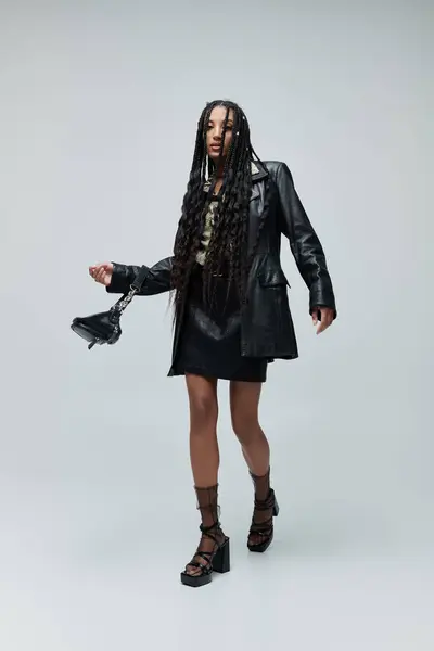 A woman strides towards the camera in a black leather jacket and skirt, a hint of animal print peeking out beneath her collar — Stock Photo