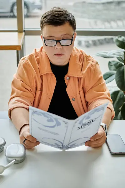 A man with Down syndrome thoughtfully selects a meal from the cafe menu. — Stock Photo