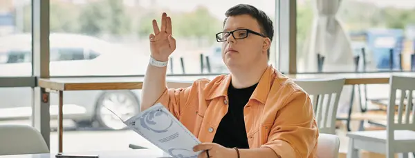 A man with Down syndrome sits in a cafe, carefully reviewing the menu and making his selection. — Stock Photo