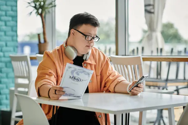 A man with Down syndrome thoughtfully chooses his meal from a menu at a cafe. — Stock Photo