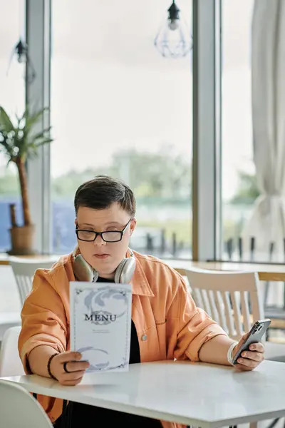A man with Down syndrome at a cafe table, reading a menu, carefully choosing a delicious meal, enjoying the experience — Stock Photo