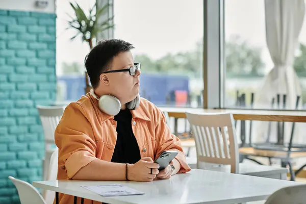 Un hombre con síndrome de Down se sienta en una mesa en un café, mirando cuidadosamente un menú. - foto de stock