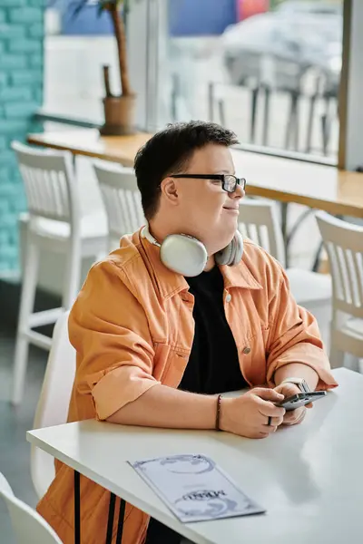 A young man with Down syndrome is sitting at a table in a cafe — Stock Photo