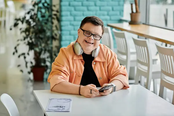 Un hombre con síndrome de Down sonríe mientras mira el menú de un café, eligiendo qué pedir. - foto de stock