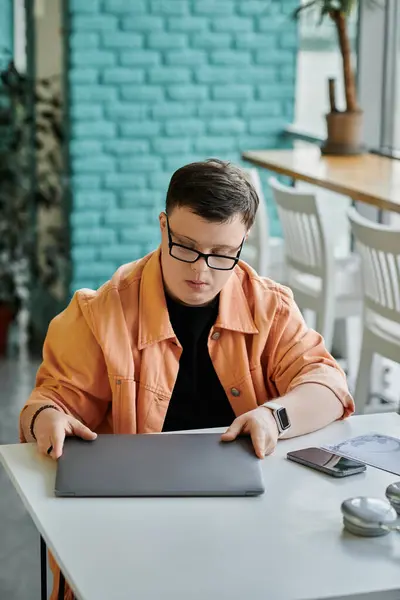A man with Down syndrome works remotely on his laptop in a cafe. — Stock Photo