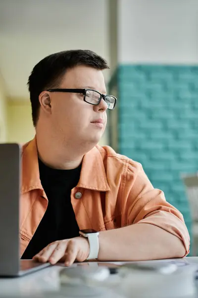 A man with Down syndrome works on his laptop in a cafe, focused on his tasks. — Stock Photo
