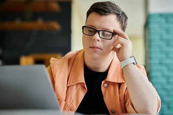 A man with Down syndrome works remotely on his laptop in a cafe. — Stock Photo