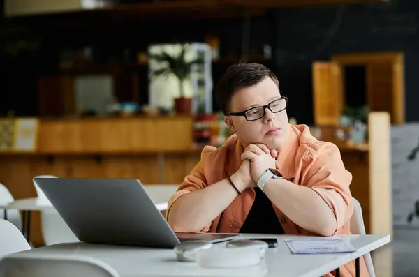 A man with Down syndrome sits in a cafe, working on his laptop. He is a freelancer, showcasing diversity and inclusion in the workplace. — Stock Photo