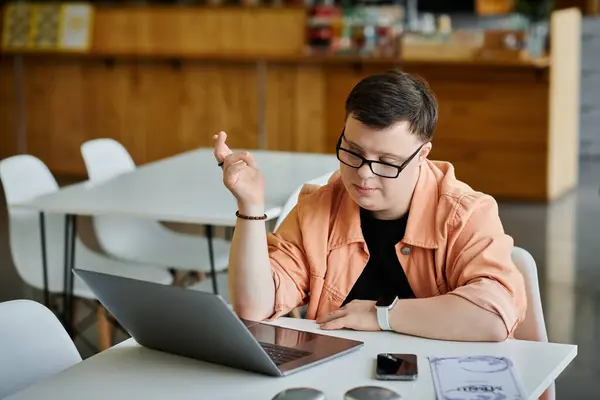 A man with Down syndrome works remotely on a laptop in a cafe. — Stock Photo