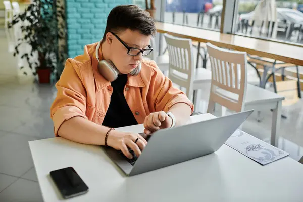 A man with Down syndrome works on his laptop in a cafe, surrounded by the energy of everyday life. — Stock Photo