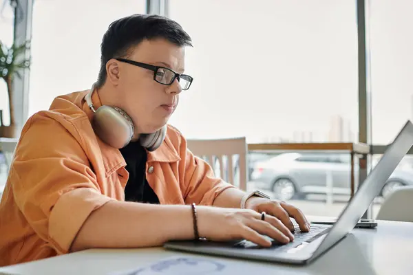 A man with Down syndrome works on his laptop in a cafe, enjoying the freedom of freelance work. — Stock Photo