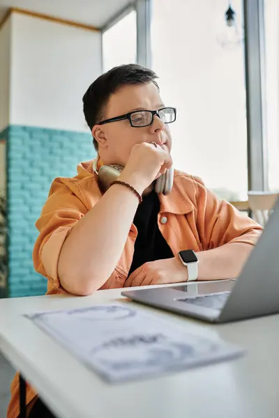 A man with Down syndrome works on his laptop at a cafe, demonstrating inclusivity and focus in the workplace — Stock Photo