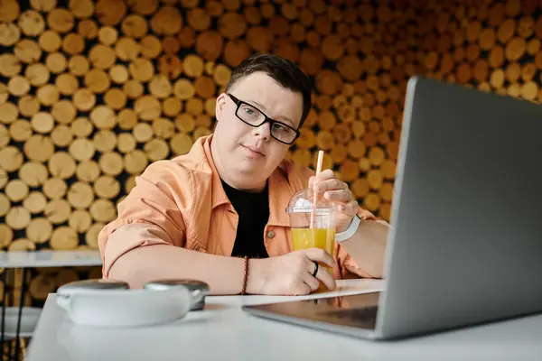 A man with Down syndrome works in a cafe on his laptop, enjoying a drink, demonstrating inclusivity and a freelance career — Stock Photo