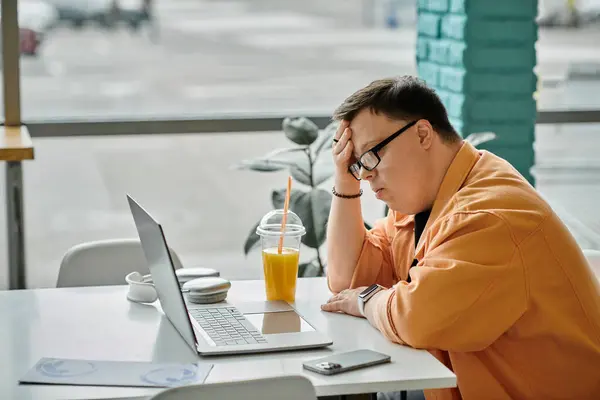 Ein Mann arbeitet in einem Café an seinem Laptop und genießt ein erfrischendes Getränk. — Stockfoto