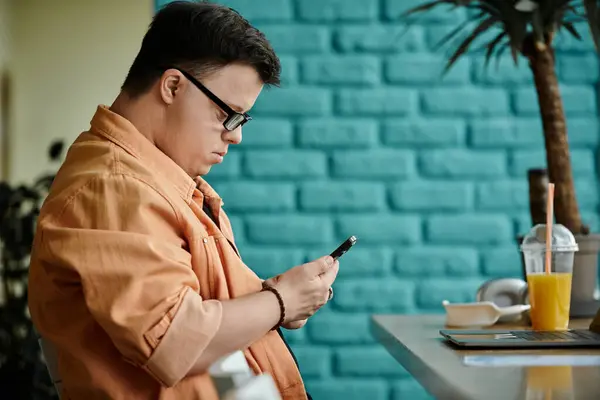 A man with Down syndrome works on his laptop while enjoying a drink in a cafe. — Stock Photo