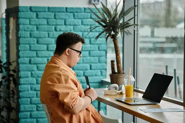 A man works remotely on his laptop in a cafe, enjoying the afternoon sunlight streaming through the window. — Stock Photo