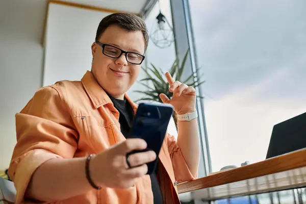 Um homem com síndrome de Down trabalha remotamente em seu telefone em um café, sorrindo e apreciando seu trabalho. — Fotografia de Stock