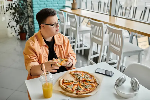 Un uomo con la sindrome di Down siede a un tavolo in un caffè, godendo felicemente una fetta di pizza. — Foto stock