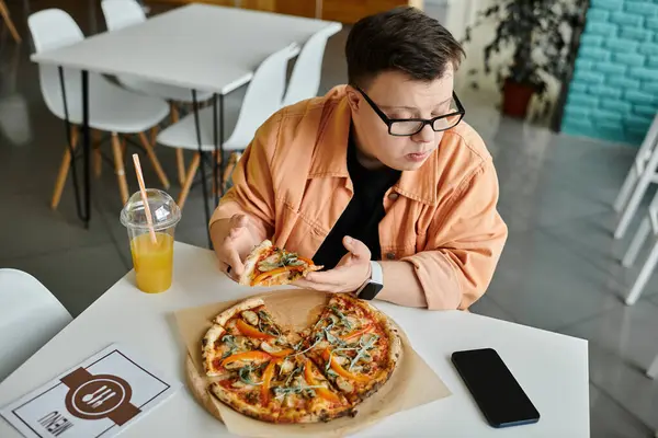 A man with Down syndrome savors a delicious slice of pizza in a cafe. — Stock Photo