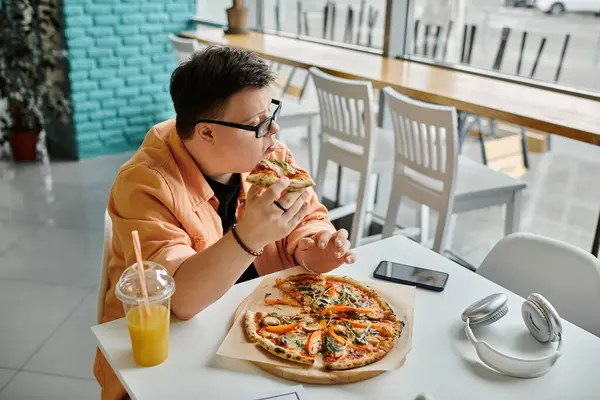 Man with down syndrome eating pizza next to smartphone and headphones in cafe — Stock Photo