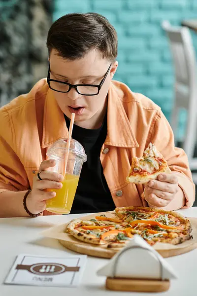 Um homem com síndrome de Down desfruta de uma fatia de pizza e uma bebida em um ambiente de café. — Fotografia de Stock