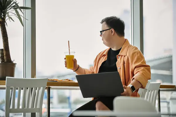 A man with Down Syndrome sits at a cafe table, enjoying a drink and a slice of pizza. — Stock Photo