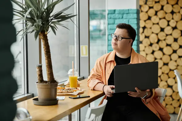 A man with Down syndrome sits in a cafe, enjoying a slice of pizza and a refreshing drink. — Stock Photo