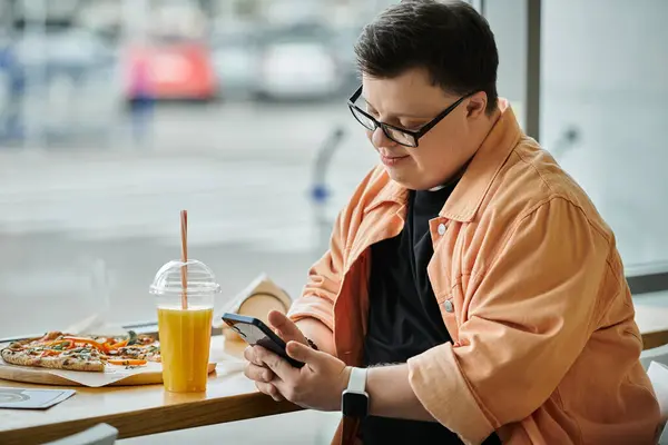 A man in a cafe checks his phone while enjoying a slice of pizza. — Stock Photo