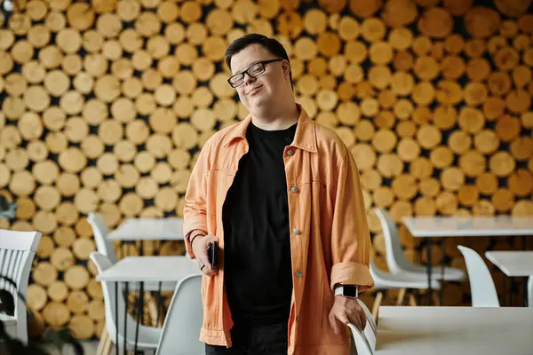 A man with Down syndrome stands in a cafe, smiling warmly and looking confident. — Stock Photo