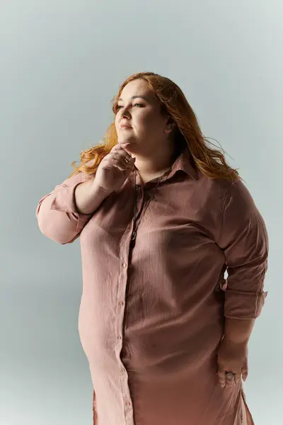 Eine Plus-Size-Frau im schicken rosa Hemd, nachdenklich nach oben starrend. — Stockfoto