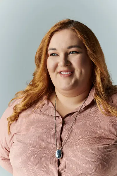 Una mujer con una blusa rosa sonríe a la cámara. - foto de stock