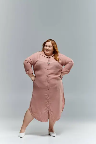A plus-size woman in a blush-colored dress poses with a confident smile. — Stock Photo