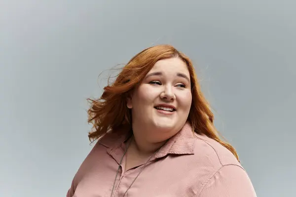 A woman with red hair smiles and looks away from the camera. — Stock Photo