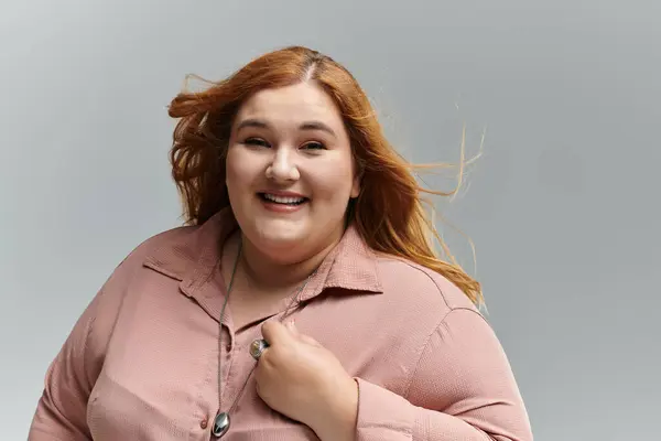 A plus-size woman with red hair smiles confidently, her windblown hair adding movement to the image. — Stock Photo