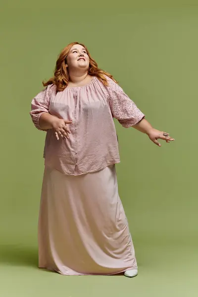 Confident plus-size woman in pink blouse and skirt gazes up — Stock Photo