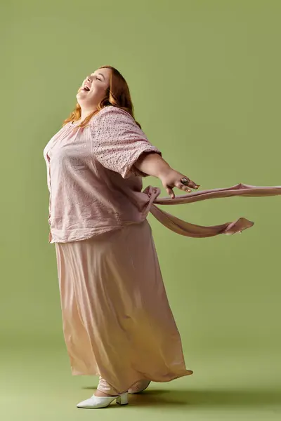 Uma mulher de vestido rosa e saltos brancos sorri brilhantemente, braços estendidos. — Fotografia de Stock