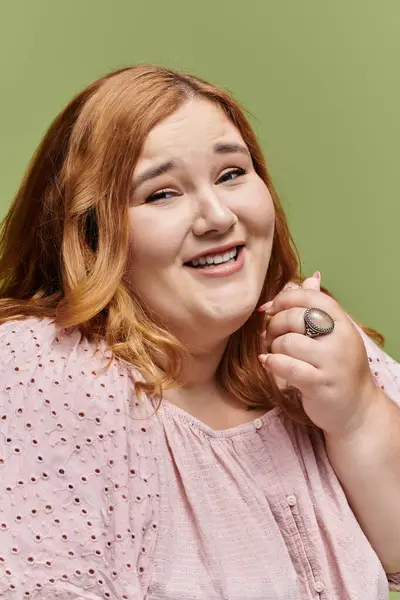 A woman with auburn hair smiles radiantly, wearing a delicate pink blouse. — Stock Photo
