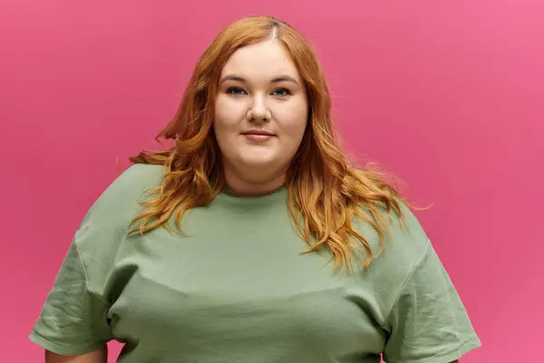 A woman with long red hair smiles confidently while wearing a green shirt. — Stock Photo