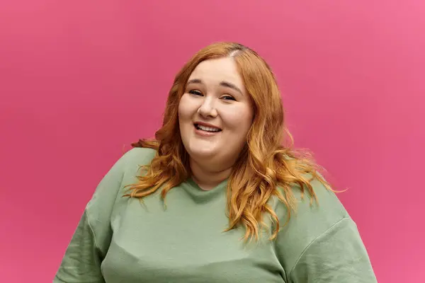 A plus size woman with long, red hair smiles at the camera while wearing a green shirt. — Stock Photo