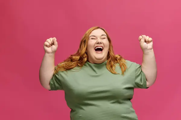 Une femme de plus grande taille aux cheveux roux rit et lève les poings dans les airs. — Photo de stock