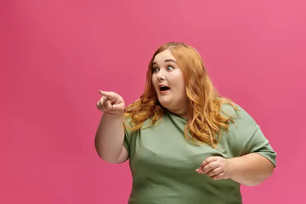 A woman points with a surprised expression. — Stock Photo