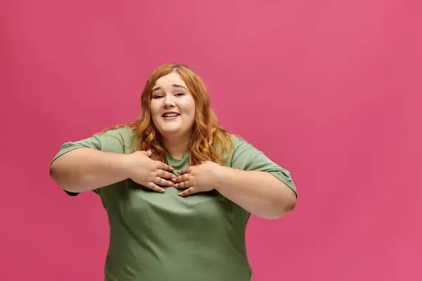 A plus size woman in a green shirt smiles and looks at the camera with her hands on her chest. — Stock Photo